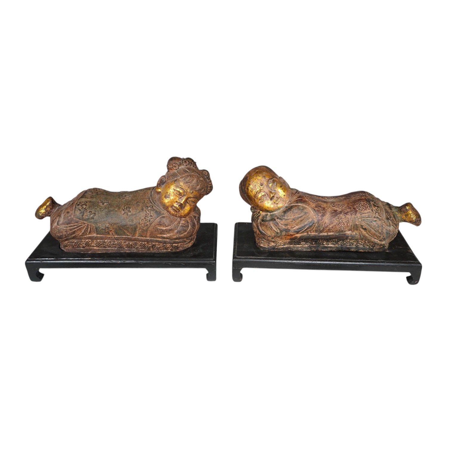 Two Chinese polychrome decorated iron pillows, modelled as sleeping children, on ebonised wood plinths, 44cm long. Condition - fair to good